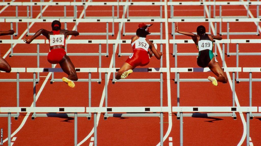 Generic shot of athletes jumping hurdles on the track