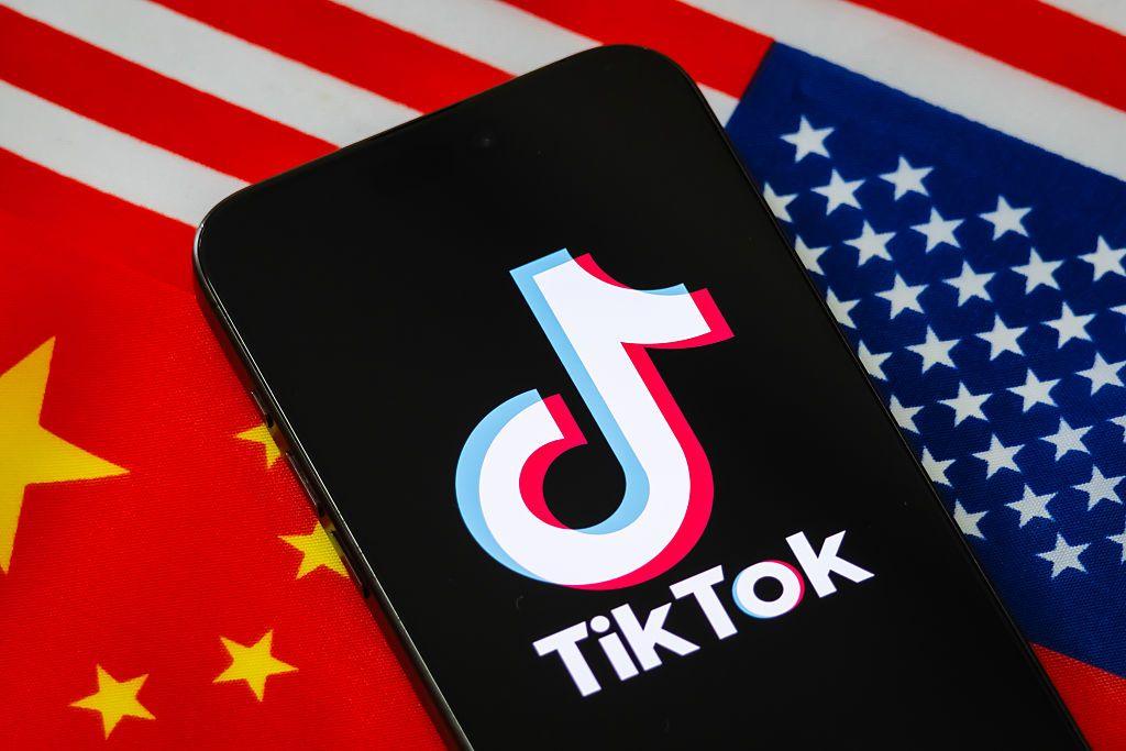 In this photo illustration, a smartphone displays the logo of TikTok, the short-video social media platform owned by China's ByteDance, with the national flags of China and the United States shown in the background.