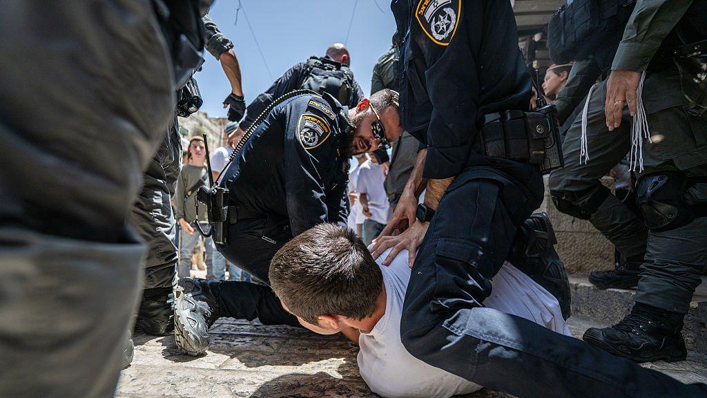 Two Israeli officers straddle a man on the ground in East Jerusalem as the Jerusalem Day parade becomes violent