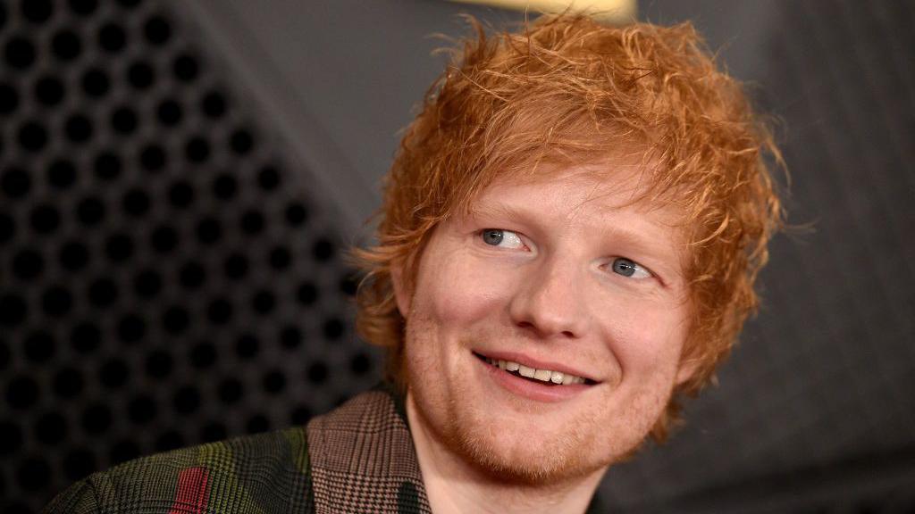 A close up photo of Ed Sheeran smiling