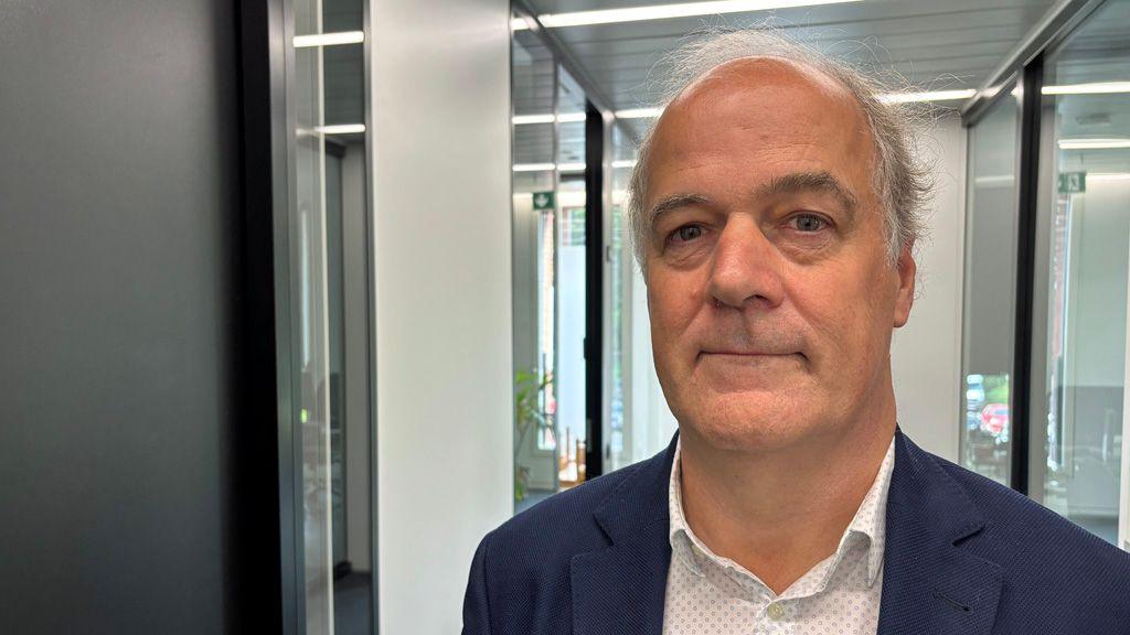 Headshot of Marc Vancoillie, head of Belgium's central directorate of drugs. He has short grey hair and is wearing a navy suit jacket and white open-necked shirt. He is standing is an office corridor.