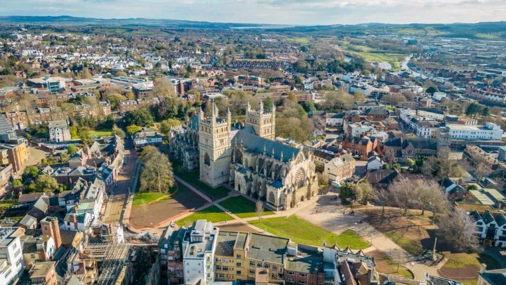 An aerial view of Exeter showing Cathedral Green in the foreground and surrounding buildings.