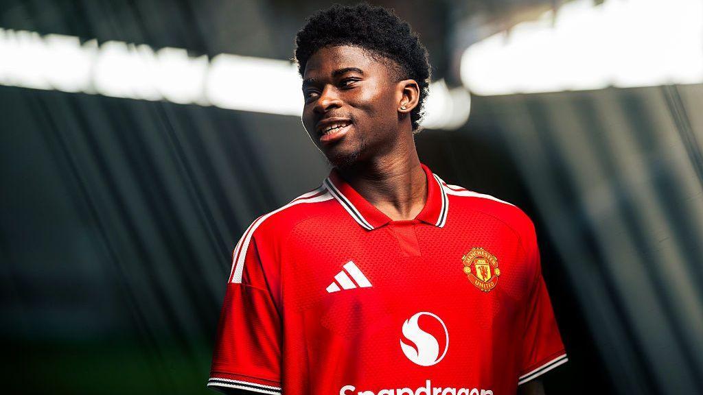 Carlos Baleba pictured smiling in a Manchester United shirt