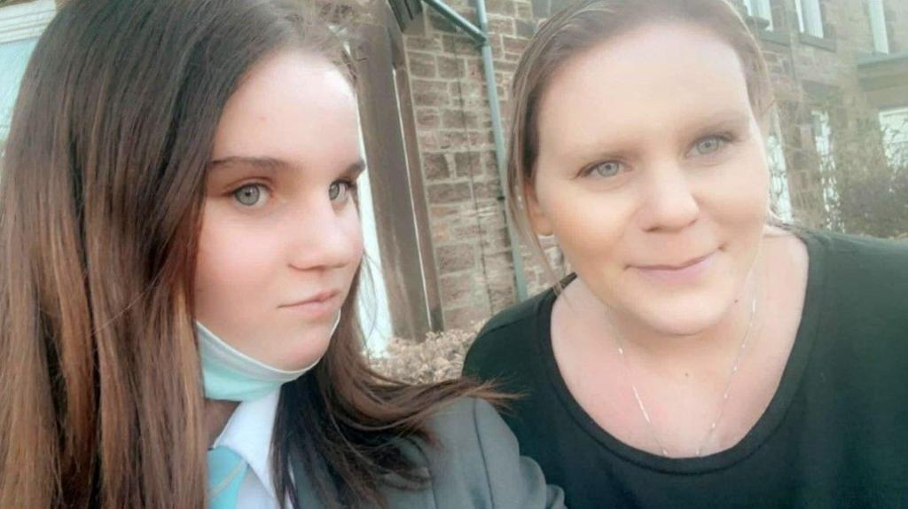 A selfie of Holly and her mother. Holly has long brown hair and Micala has blond hair, both are looking at the camera smiling.
