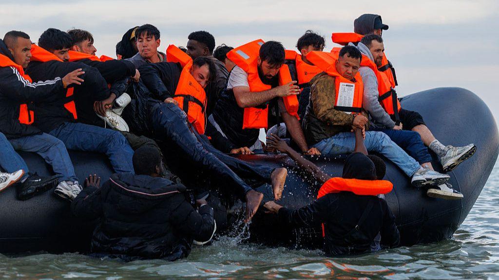 People clambering onto a small boat in the Channel near France