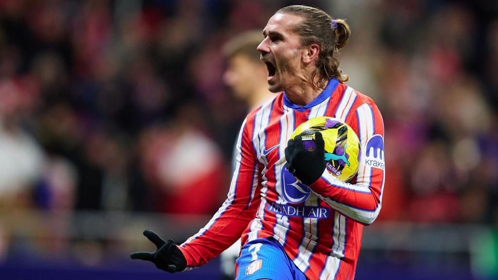 Antoine Griezmann holding a football and celebrating