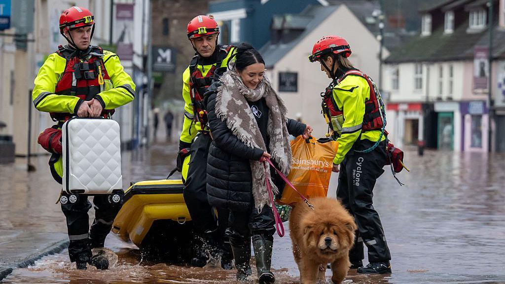 A woman and her dog being helped by emergency service workers in Monmouth.
