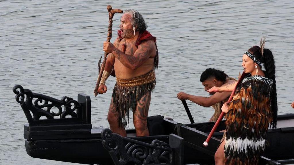 A boat carries Māori warriors under the bridge at Waitangi after a service to commemorate the national day