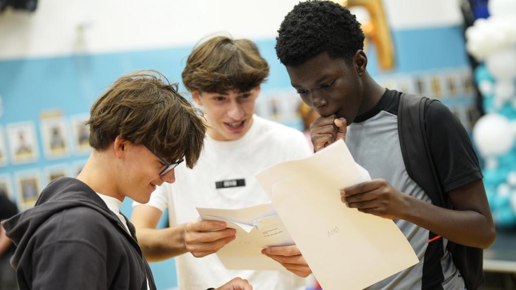 Three pupils look at their GCSE results sheet