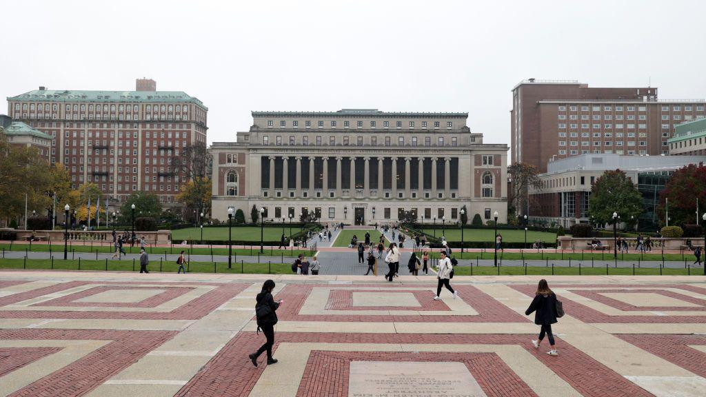 People walk on side walk outside university building