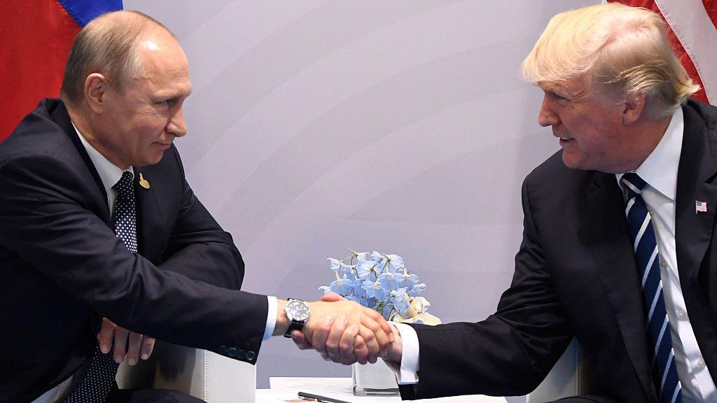 Vladimir Putin and Donald Trump shake hands across a table at the G20 summit in Hamburg, Germany, in July 2017 as they look at each other directly. 