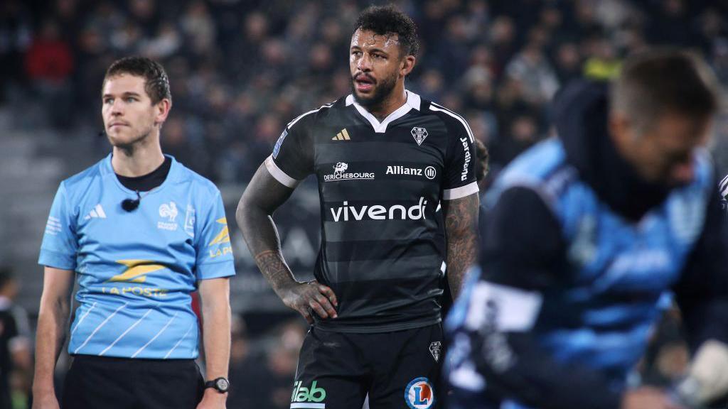Courtney Lawes stands with his hands on his hips while playing for Brive, standing next to the referee