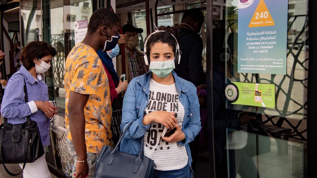 A woman wearing a protective mask steps off a tram in the center of the Moroccan capital Rabat on June 16, 2020.