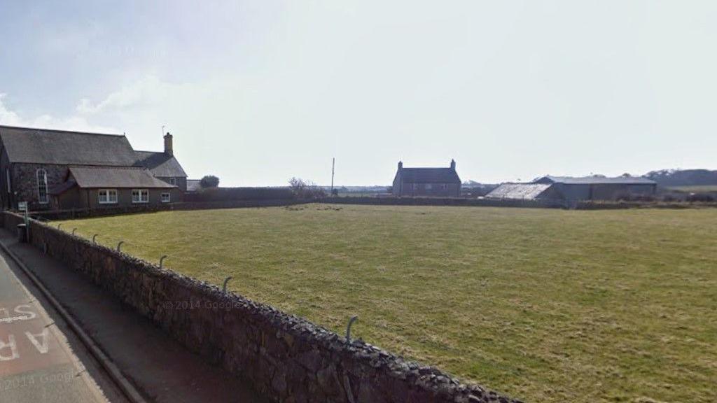 An image of a field with building and brick wall surrounding it in Botwnnog, Gwynedd