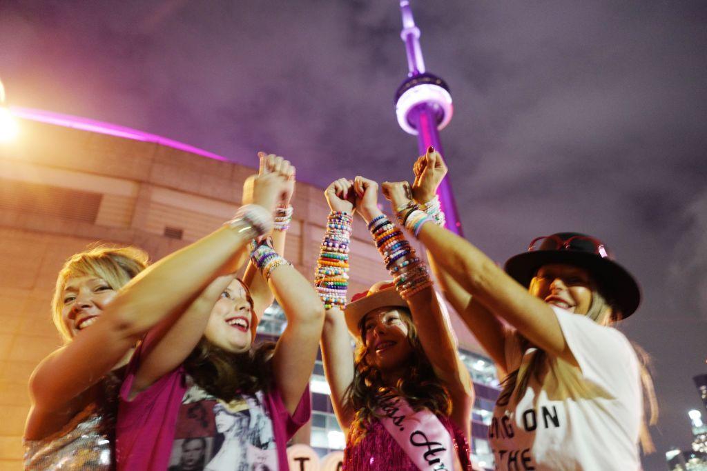 A group of young fans display the friendship bracelets they've collected at a Taylor Swift concert