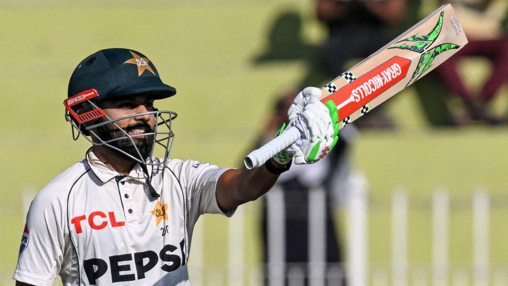 Pakistan batter Saud Shakeel raises his bat to celebrate hitting a century