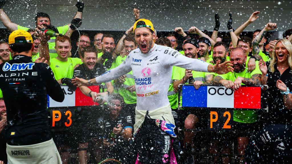 Champagne is sprayed over drivers Esteban Ocon and Pierre Gasly as the Alpine team celebrate finishing second and third at the Sao Paulo Grand Prix