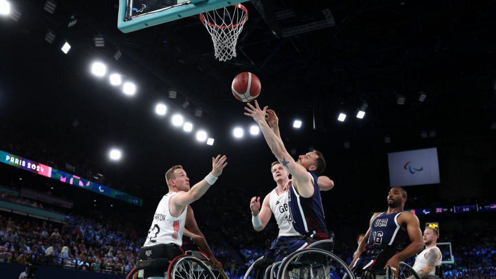 Steve Serio of the United States shoots at the basket while Gregg Warburton tries to intercept during the Paralympic wheelchair basketball gold-medal match