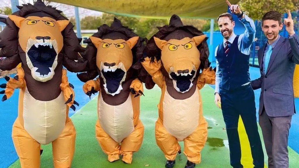 school-teacher-with-standing-next-to-cardboard-cut-out-and-staff-in-lion-costumes.