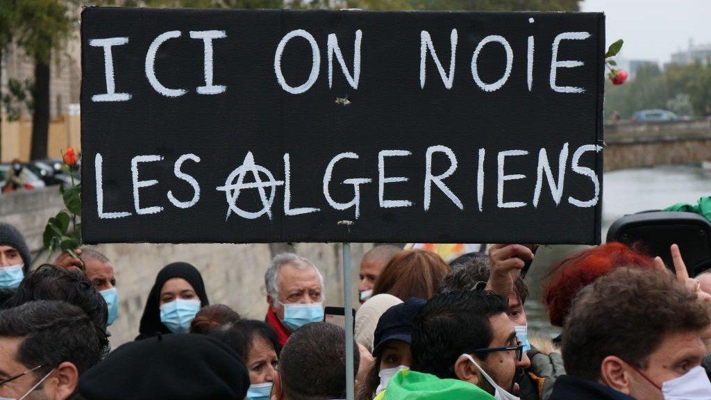 Placard saying: "Here we drown Algerians" seen at a remembrance ceremony to mark the 59th anniversary of the 1961 Paris massacre at the Pont Saint-Michel bridge over the River Seine in Paris, France - 17 October 2020