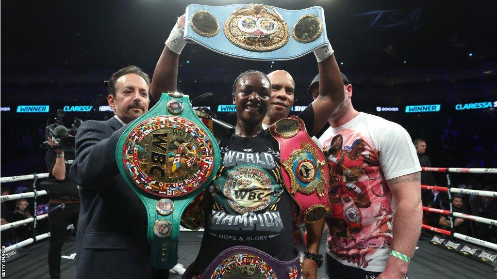 Claressa Shields posing with all four middleweight belts