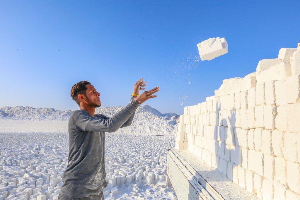 A worker throws a lump of limestone on top of a very large pile at a quarry site in Minya, Egypt - Saturday 14 December 2024