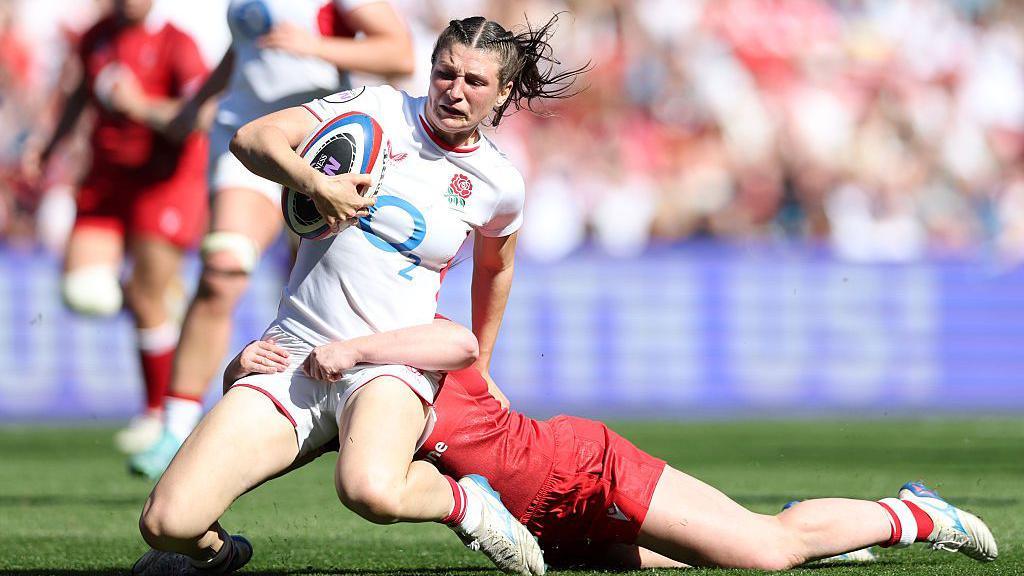 Flo Robinson is tackled by a Wales player 