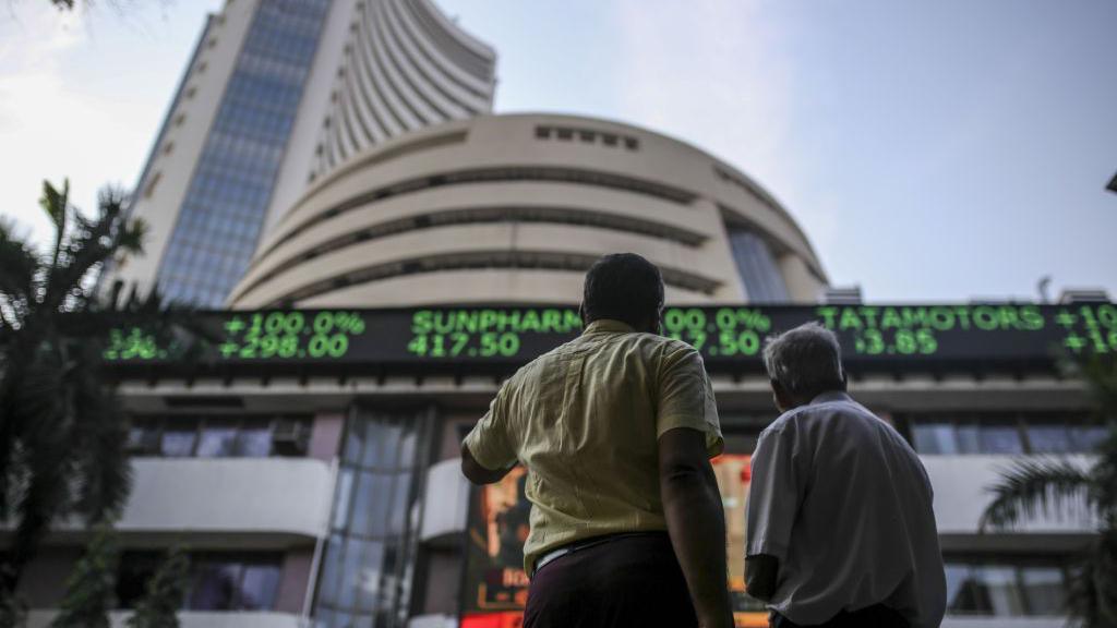 Pedestrians look up at an electronic screen and a digital ticker board at the Bombay Stock Exchange building in Mumbai.