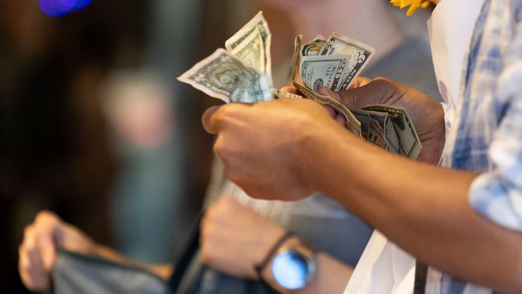 A customer holds dollars at the Pike Place Market in Seattle, Washington, US, on Thursday, July 4, 2024. 