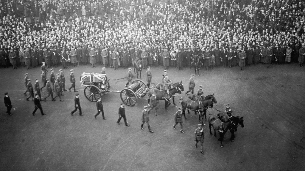 The coffin of the unknown warrior placed on a gun carriage being pulled by horse front of a large crowd of people