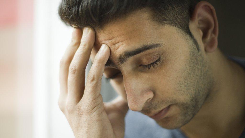 Man with his hand against his head