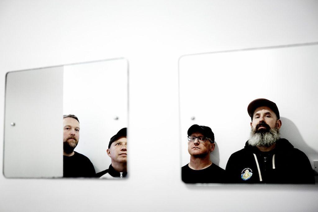 Mogwai, dressed in black, are reflected at an oblique angle in a pair of rectangular mirrors