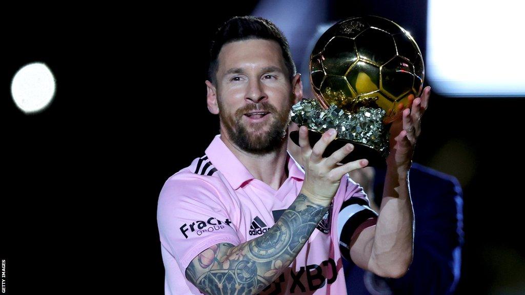 Lionel Messi in an Inter Miami shirt holding the Ballon d'O