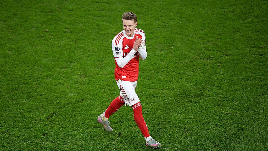 Martin Odegaard smiles as he applauds the Arsenal supporters