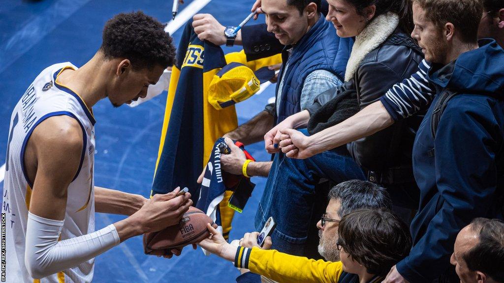 Mets 92's French power forward Victor Wembanyama (L) signs a fan's ball after the French Elite Basketball match between Boulogne-Levallois Metropolitans 92 and Sluc Nancy, in Levallois-Perret, near Paris, France