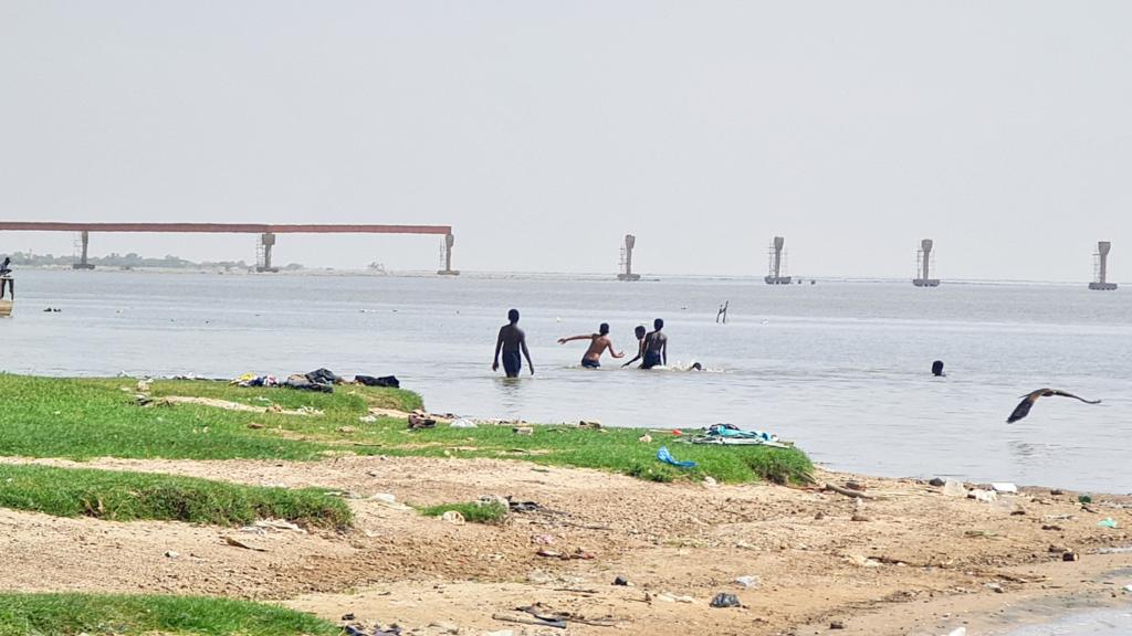 People swimming in the White Nile River near the al-Dabbasin bridge in Khartoum, Sudan - 23 May 2023