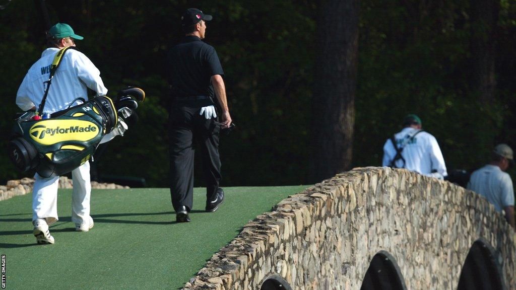 Mike Weir and his caddie Brennan Little walk across a bridge at Augusta