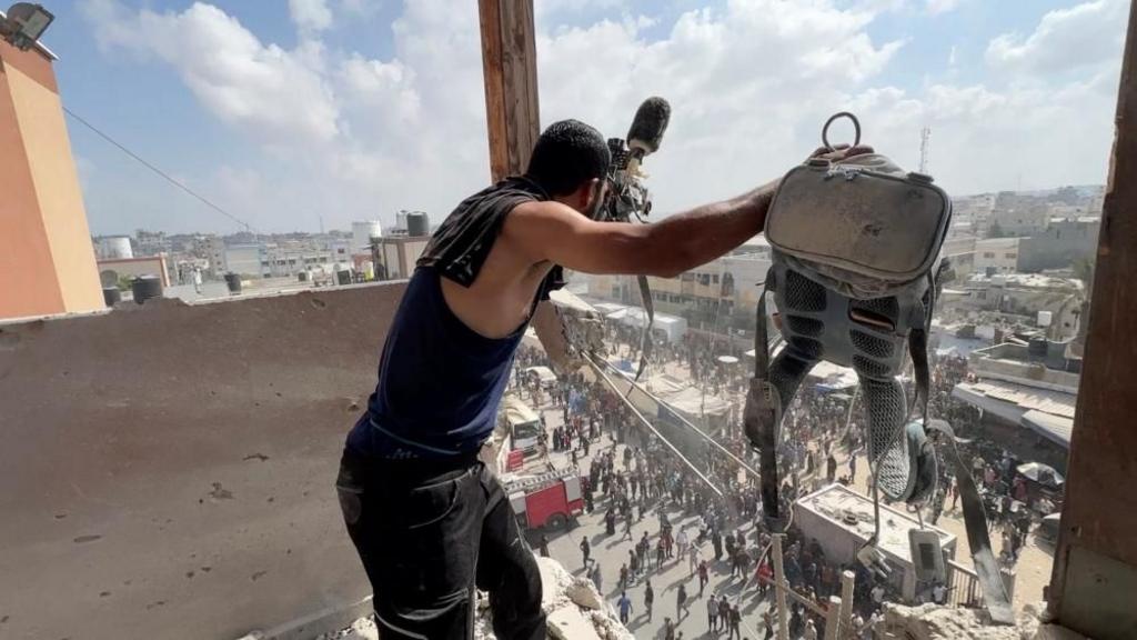A man holds equipment said to be used by a Palestinian cameraman as he looks down from a ruined building