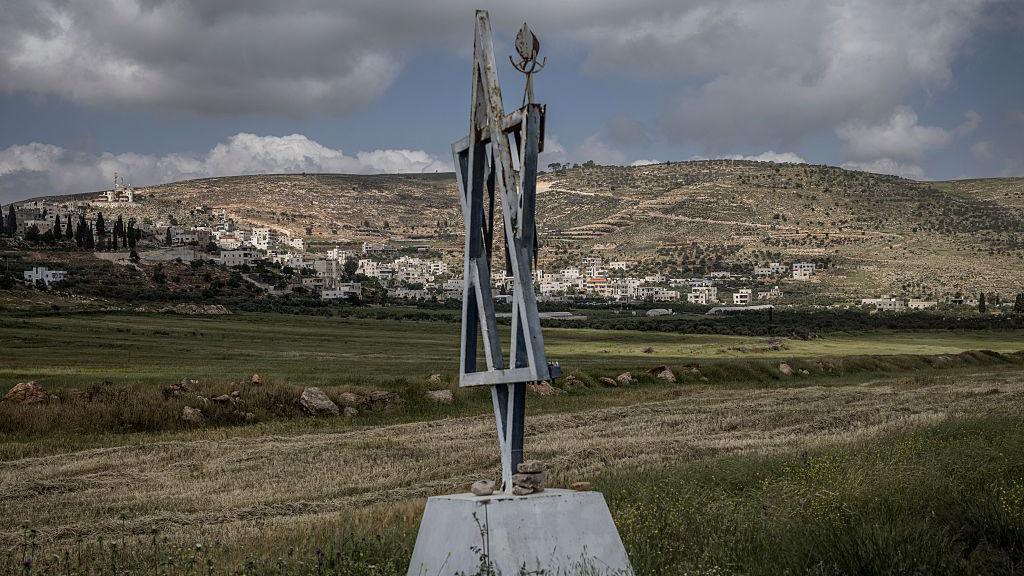File photo showing a metal Star of David placed outside the Malachei HaShalom settler outpost near the Palestinian village of al-Mughayyir (in the background), in the occupied West Bank (20 April 2026)