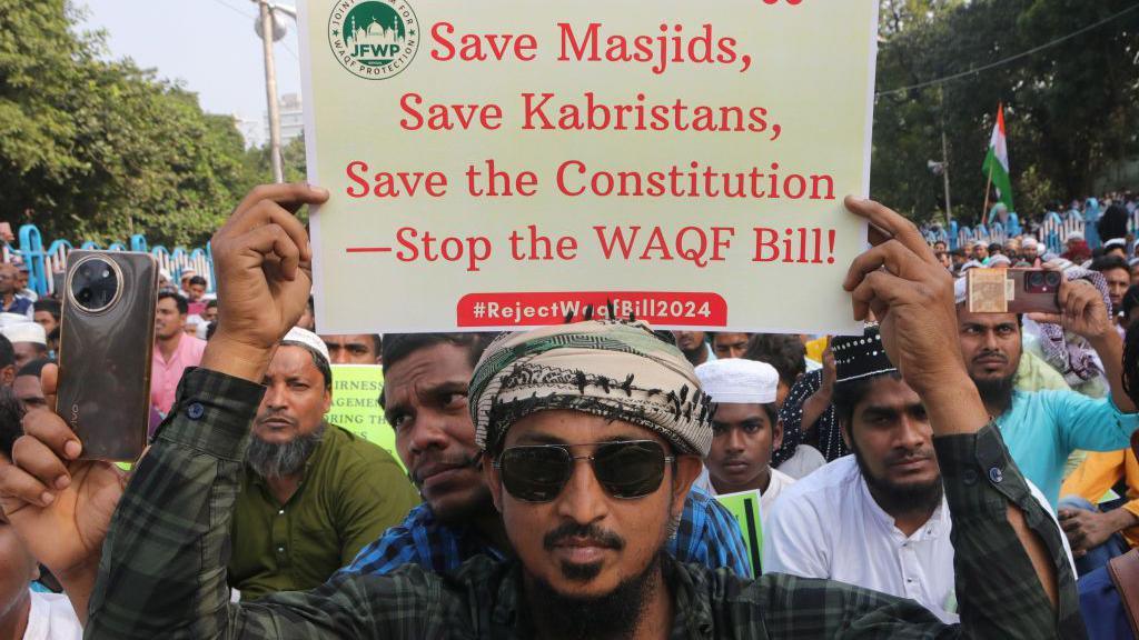 A man holds up a placard opposing the new Waqf bill, surrounded by more protesters