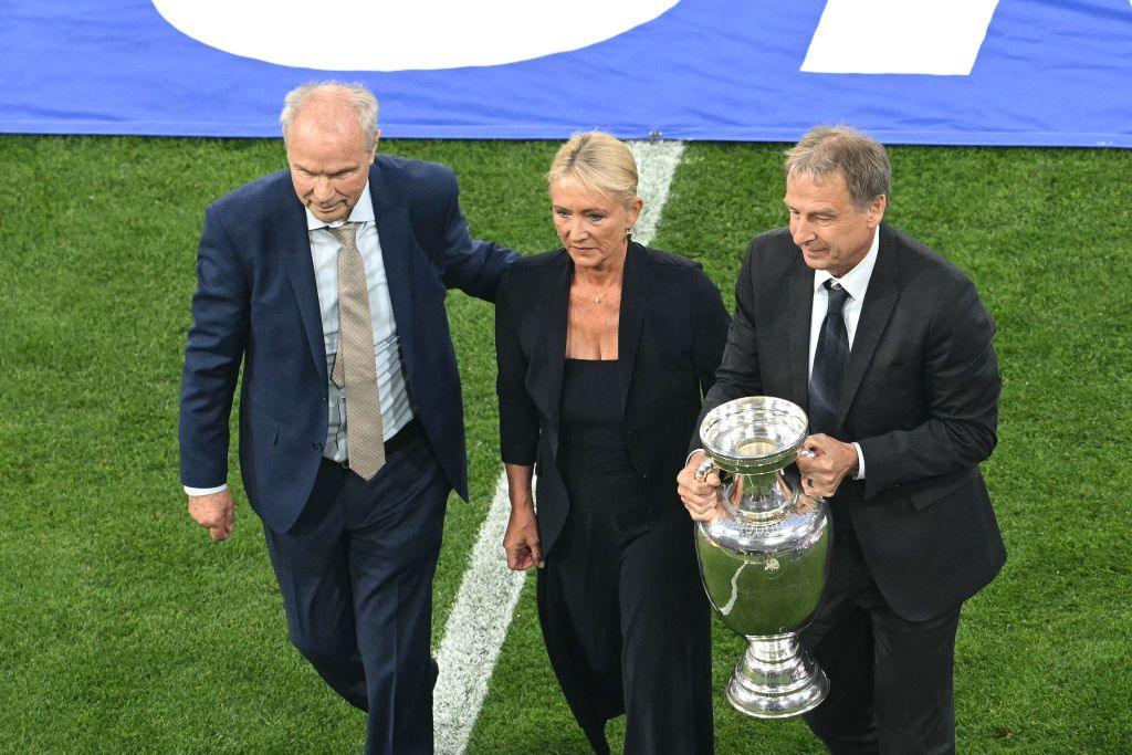 Bernard Dietz and Jurgen Klinsmann, alongside Franz Beckenbauer's widow Heidi, bring out the European Championship trophy