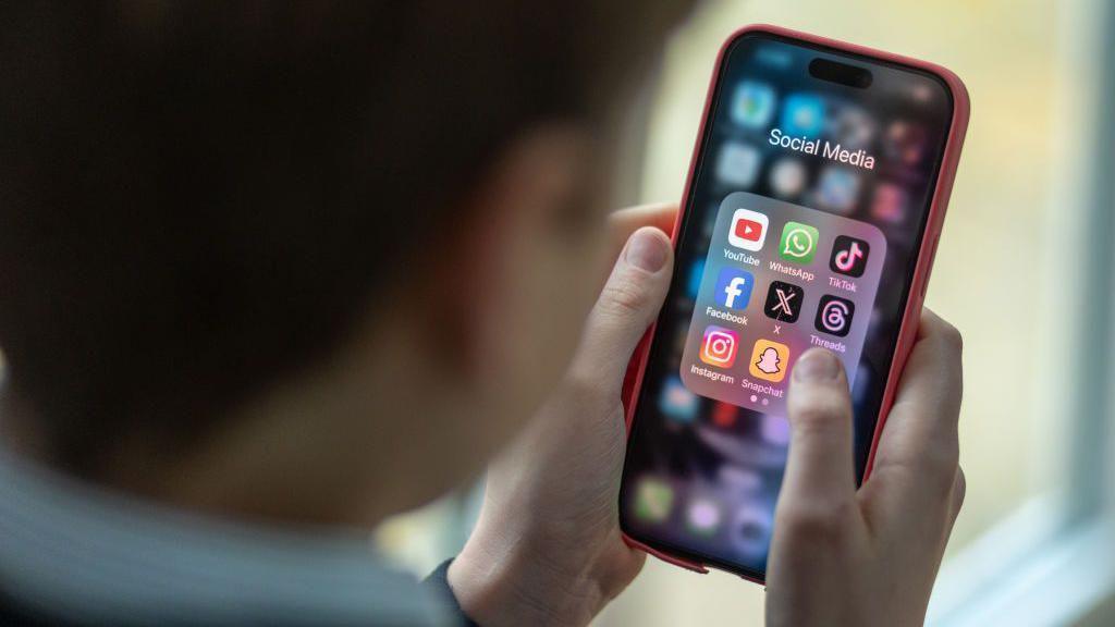 A boy looking at apps on his phone.