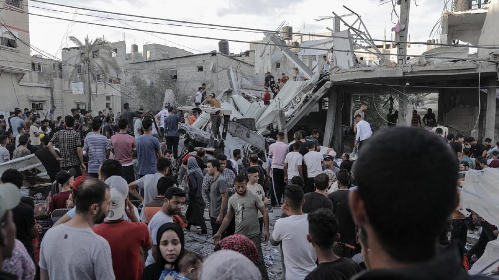 Palestinians search for bodies and survivors in the rubble of a residential building leveled in an airstrike, in the Khan Younis refugee camp in the southern Gaza Strip, 21 October 2023