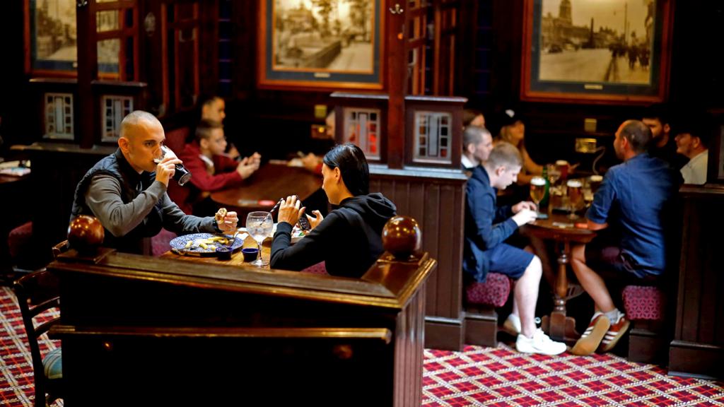 Customers sit in a pub