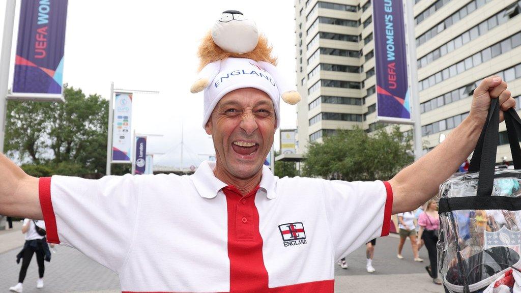 A male football fans holds his arms up as he stands on Wembley Way