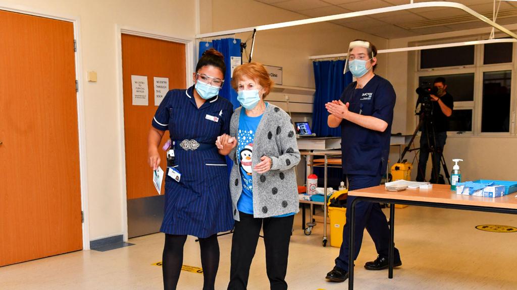 Margaret Keenan holding hands with the nurse