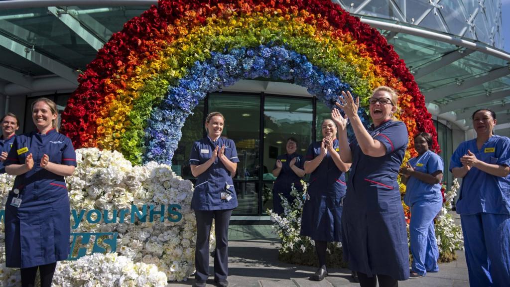 Nurses helping to unveil a rainbow floral display outside the University College Hospital in London