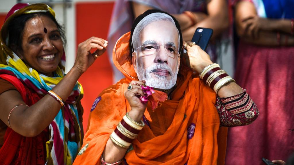 An Indian political supporter wears a mask of Indian Prime Minister Narendra Modi as she participates in Bharatiya Janata Party (BJP) President Amit Shah's road show in Ahmedabad on March 30, 2019. - Amitbhai Shah participated in a road show in Ahmedabad before filing his nomination papers for the forthcoming Lok Sabha elctions in Gandhinagar, local reports said