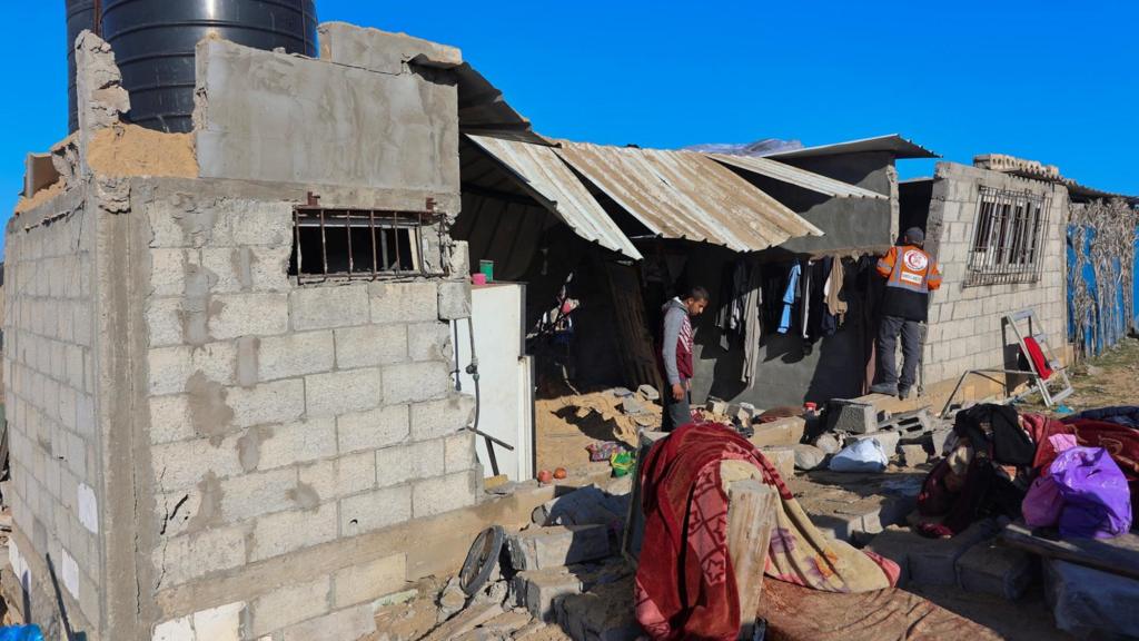 Palestinian men stand in a building as others inspect the site of Israeli strikes on Al-Mawasi where displaced Palestinians shelter, according to a health ministry official, west of Khan Younis in the southern Gaza Strip