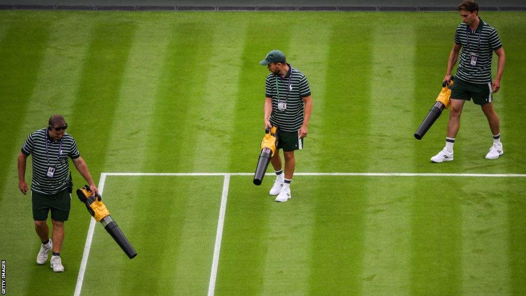 Ground staff try to dry the court with dryers